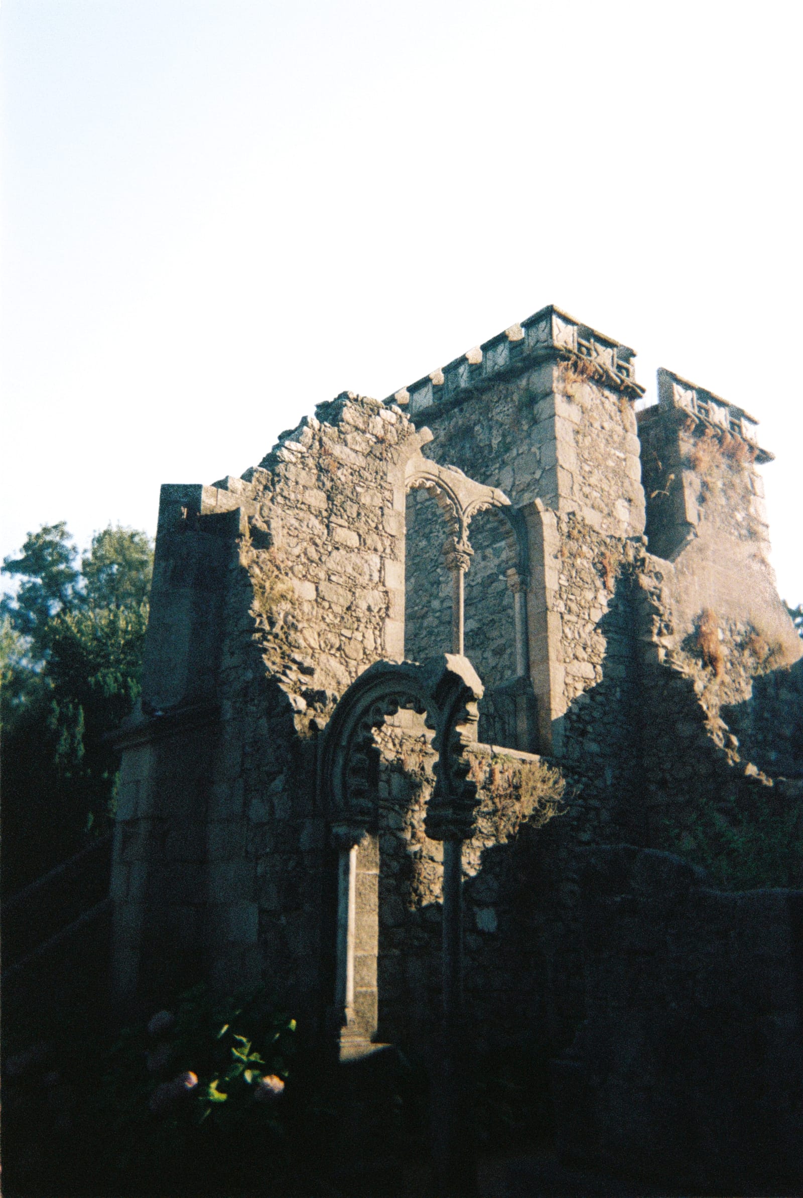 Sunlit Gothic stone ruins rising from deep shadow beneath an open sky in Sintra, Portugal