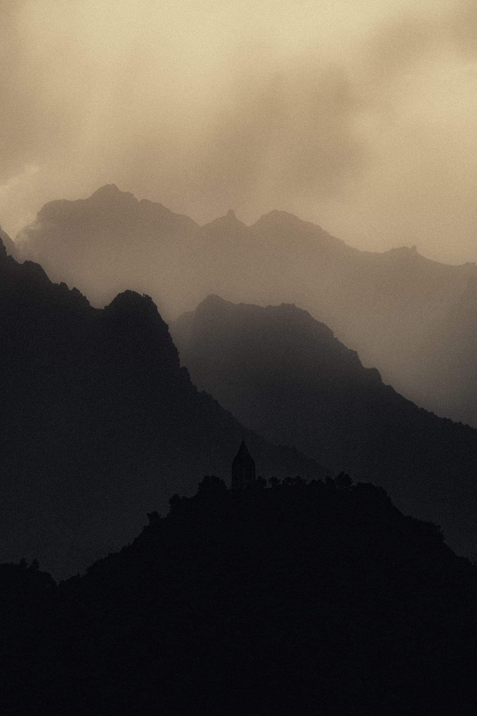A small chapel silhouetted on a Madeira ridge beneath overlapping mountain peaks.
