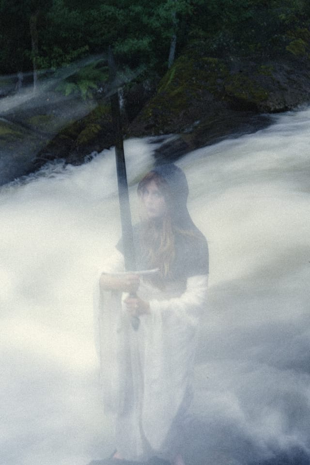 A chainmail-clad figure appearing through soft motion and white water