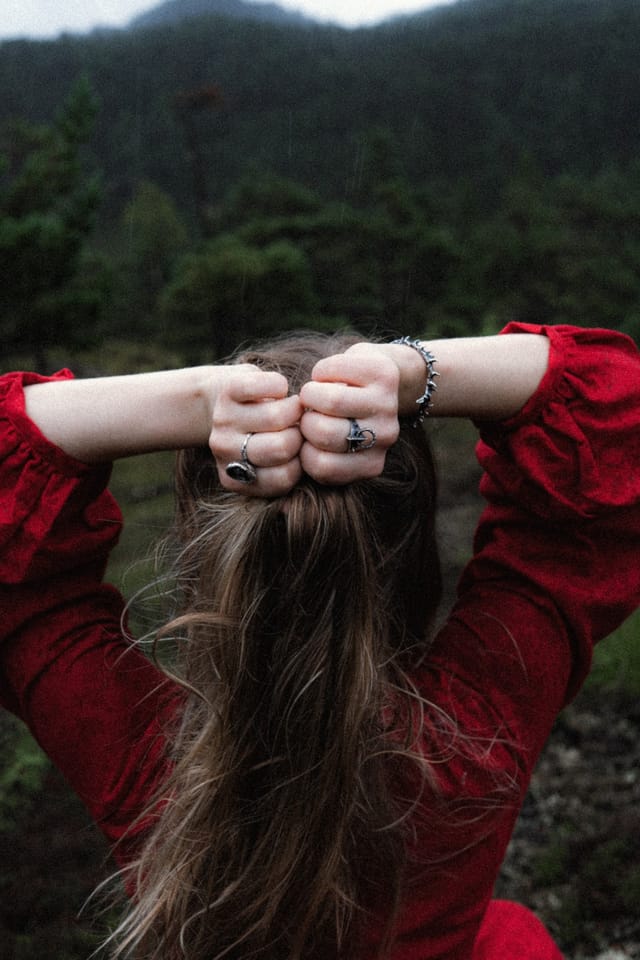 Close view of wet hair and ringed hands against the back of a red dress
