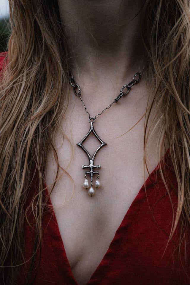 Silver pendants resting against wet skin and the neckline of a red dress