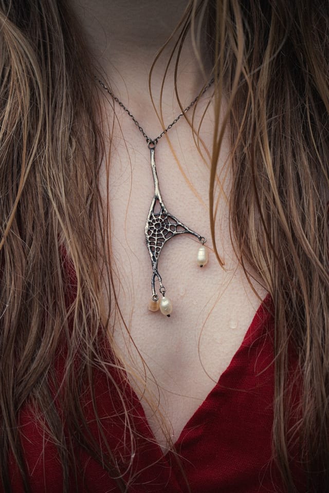 A silver pendant and chain resting against the wet neckline of a red dress