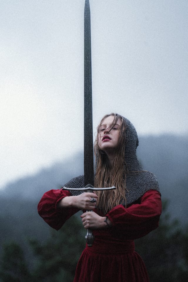 A small red figure and upright sword isolated in a wide misty meadow