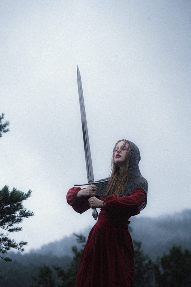 A distant sword-bearer in red partly hidden by wet meadow plants