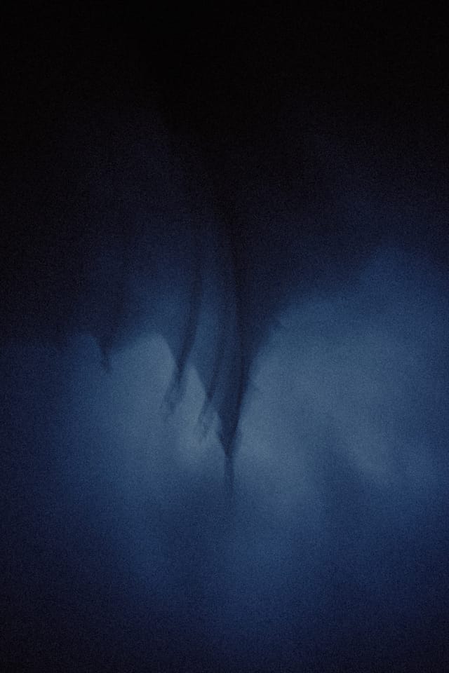 Dark carved roof finials of a stave church dissolving into blue fog