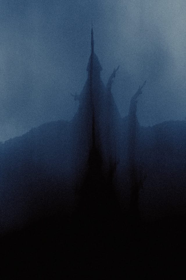 A tall stave church spire fading into a deep blue veil of mist