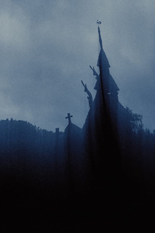 The carved spire of a stave church standing against a stormy blue sky