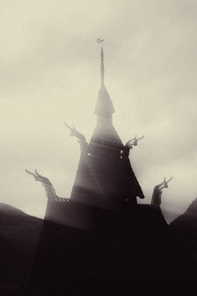 A stave church tower breaking through bright mist in a stark silhouette