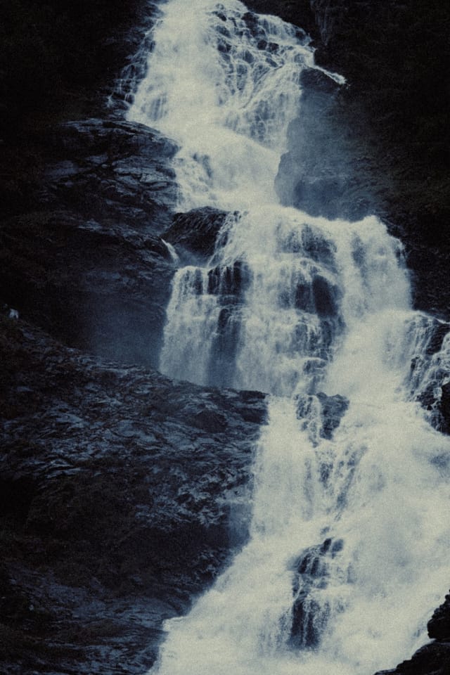 Foaming water descending in layered sheets over a steep rock face