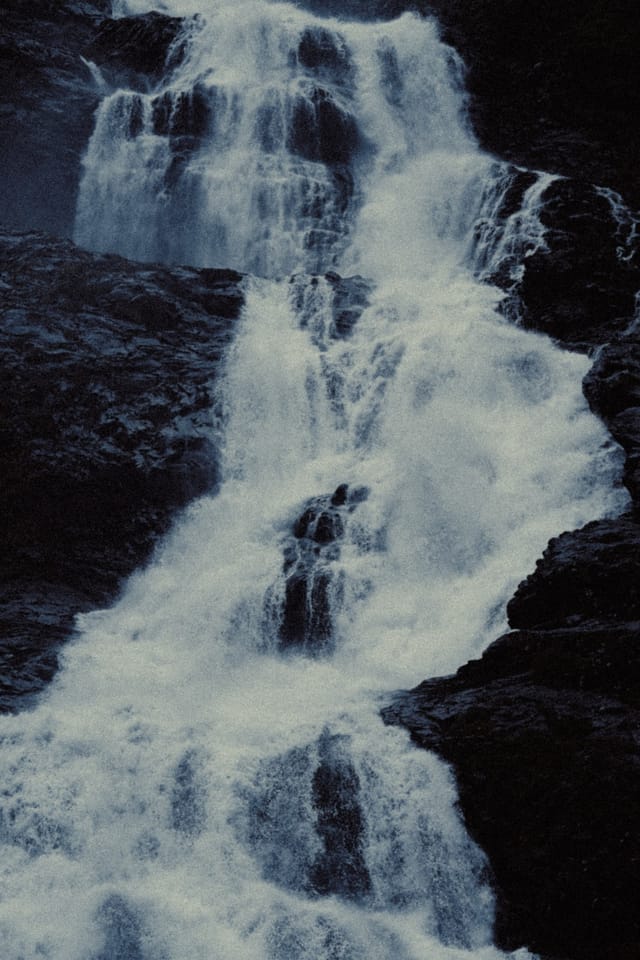 A bright Norwegian waterfall cutting diagonally across dark stone