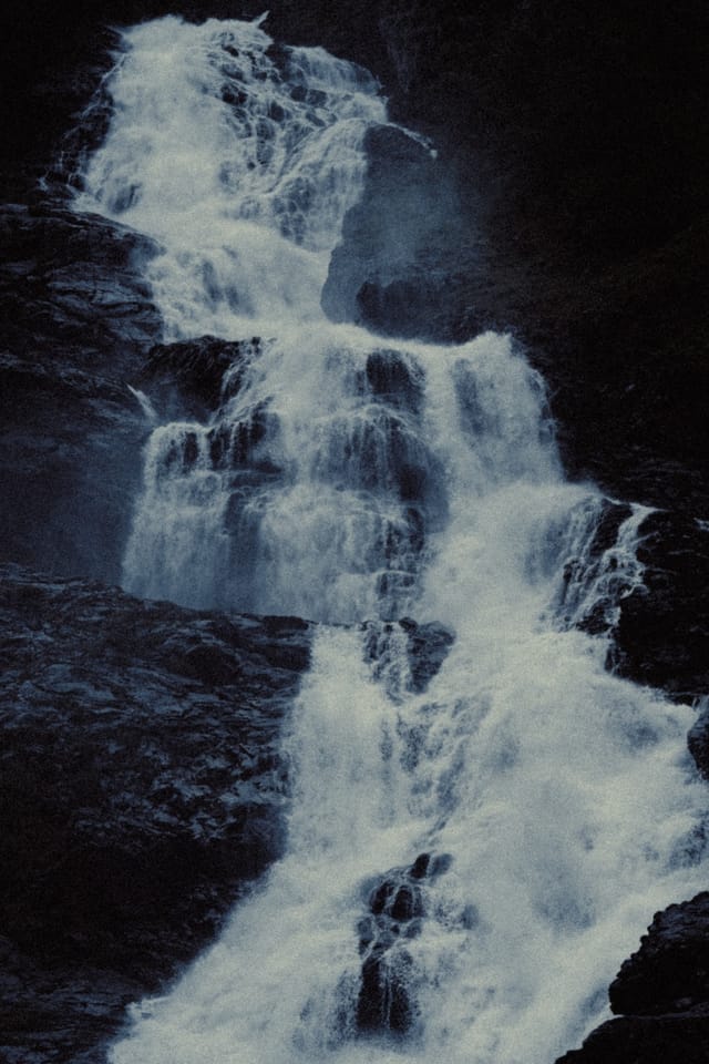 A close view of a waterfall bursting over successive black ledges