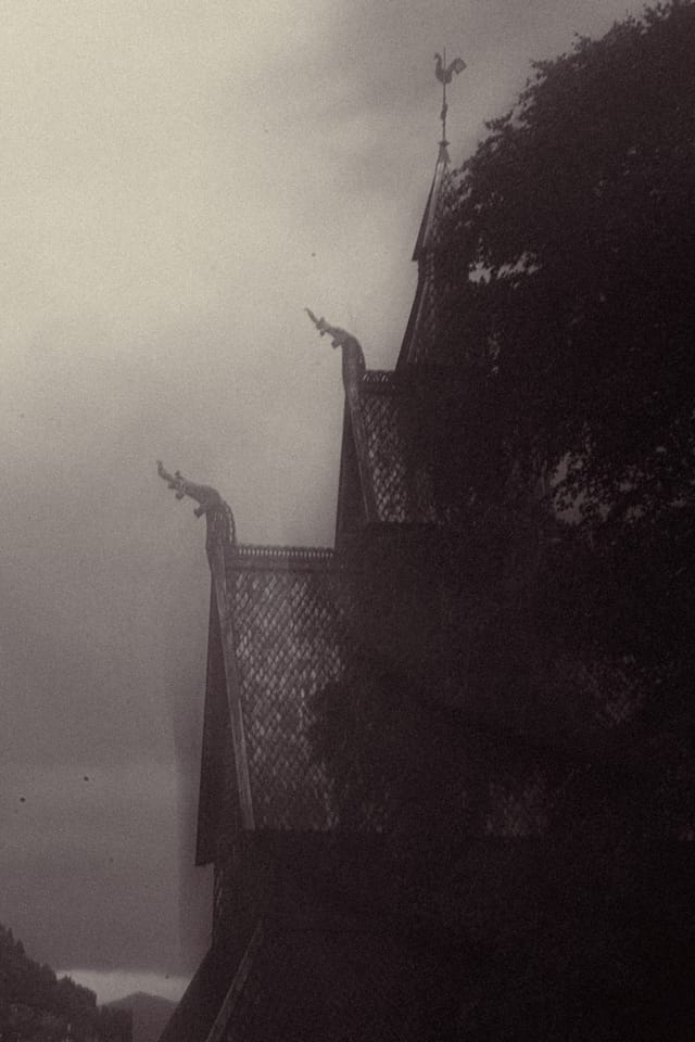 The edge of a stave church roof fading into warm mountain haze